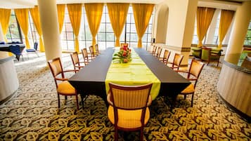 A conference room with a long table, yellow chairs, and a floral centerpiece.