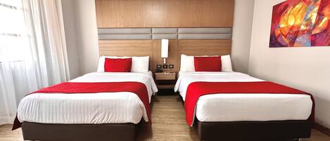 Habitación de hotel con dos camas, cabecero de madera, un cuadro en la pared y una ventana con cortinas.