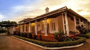 A colonial-style building with a covered porch, arched windows, and a tiled roof. - Gateway Coonoor (Coonoor)