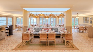 A spacious dining area with a high ceiling, large windows, and a piano.