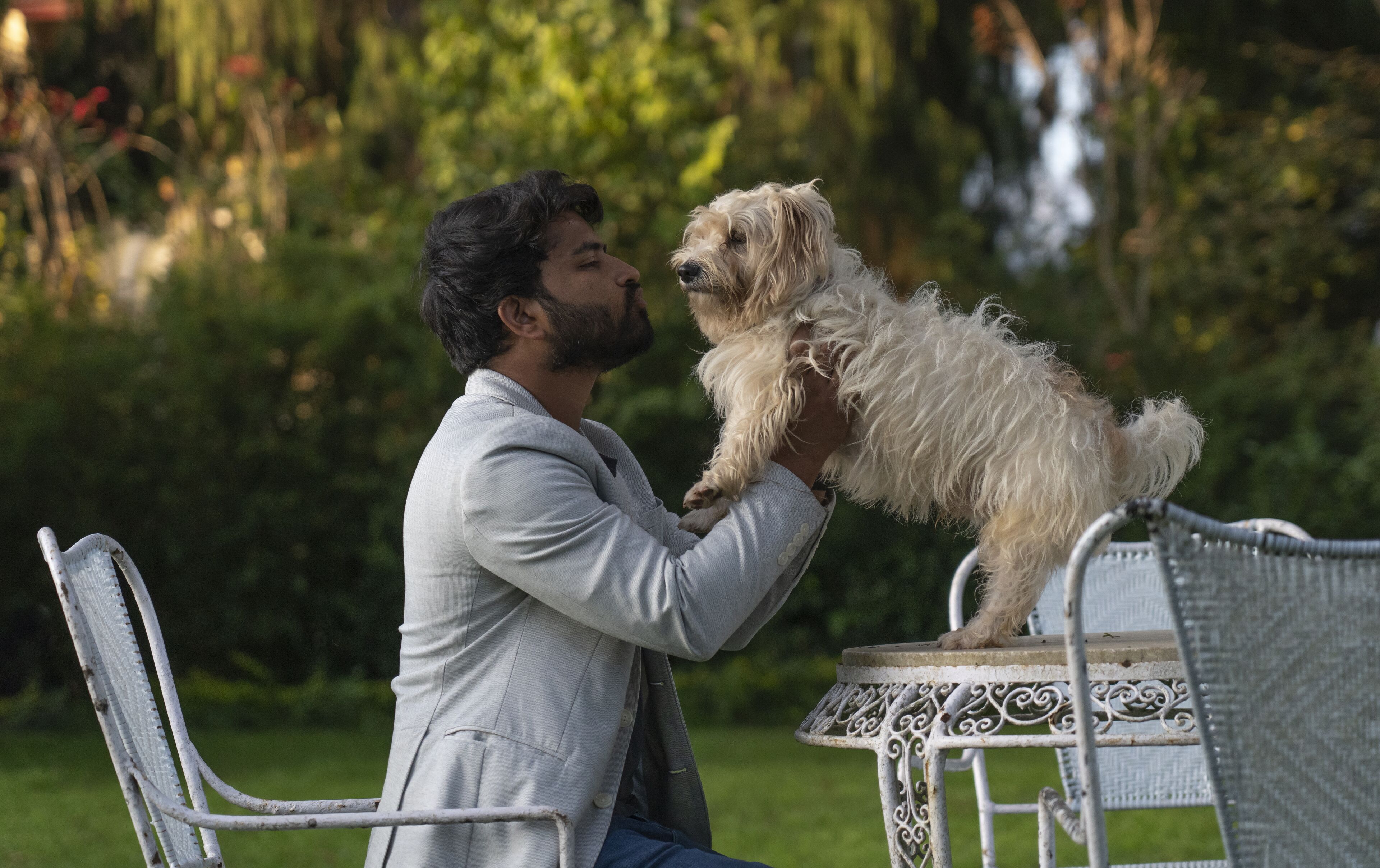 A person holding a small dog on a chair outdoors.