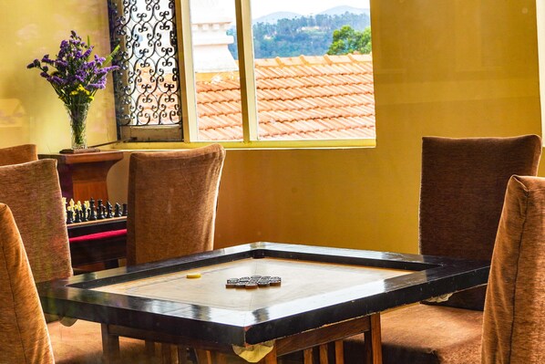 A room with a table for board games, a chessboard, and a vase with flowers.