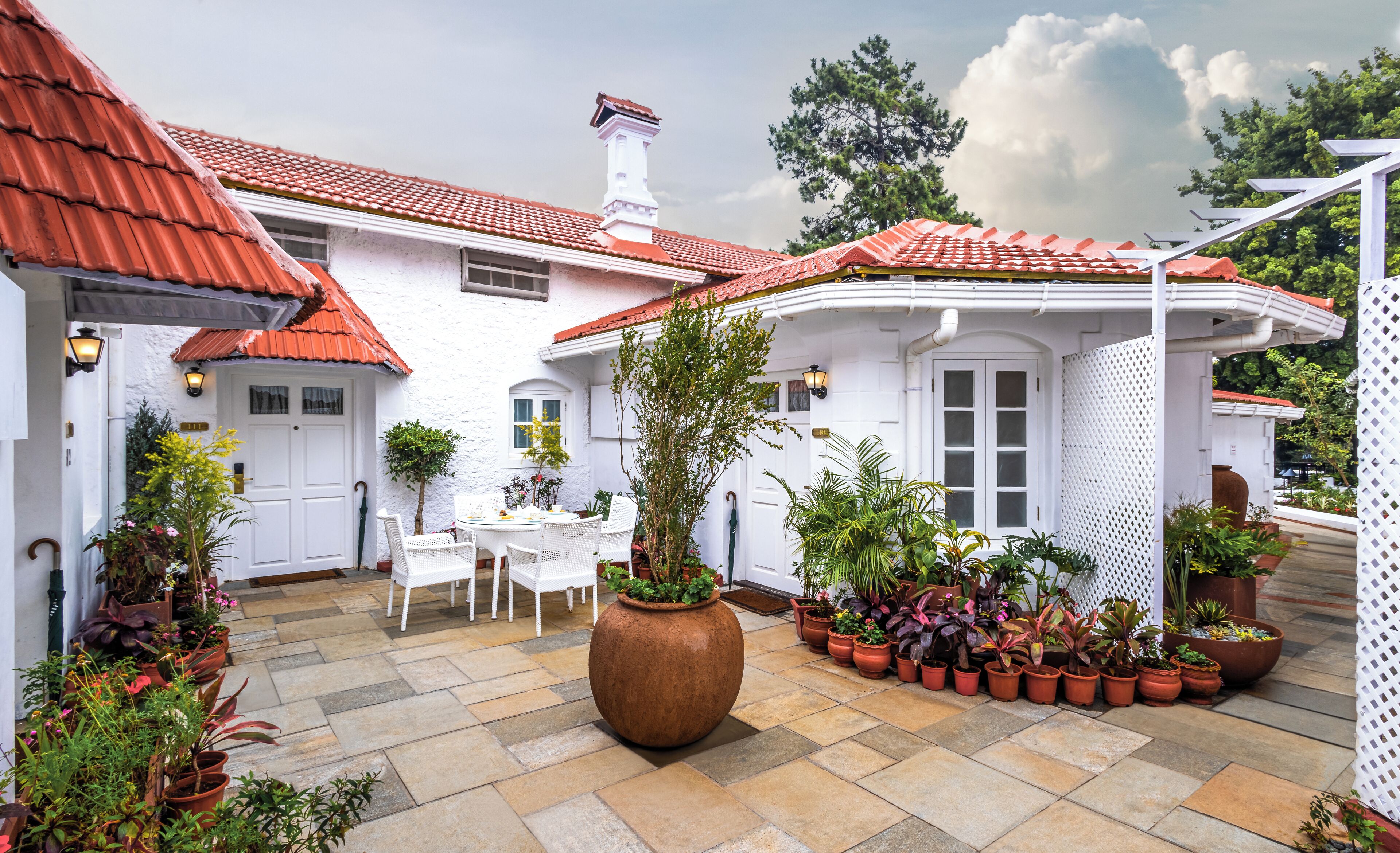 A courtyard with a white building, red-tiled roofs, and potted plants.