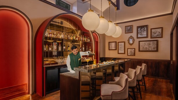 A bar area with a bartender, shelves of liquor, and a seating area with chairs. - Gateway Coonoor (Coonoor)