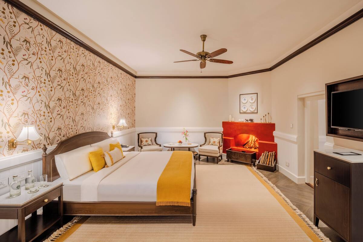 A hotel room with a bed, a fireplace, a television, and a ceiling fan.