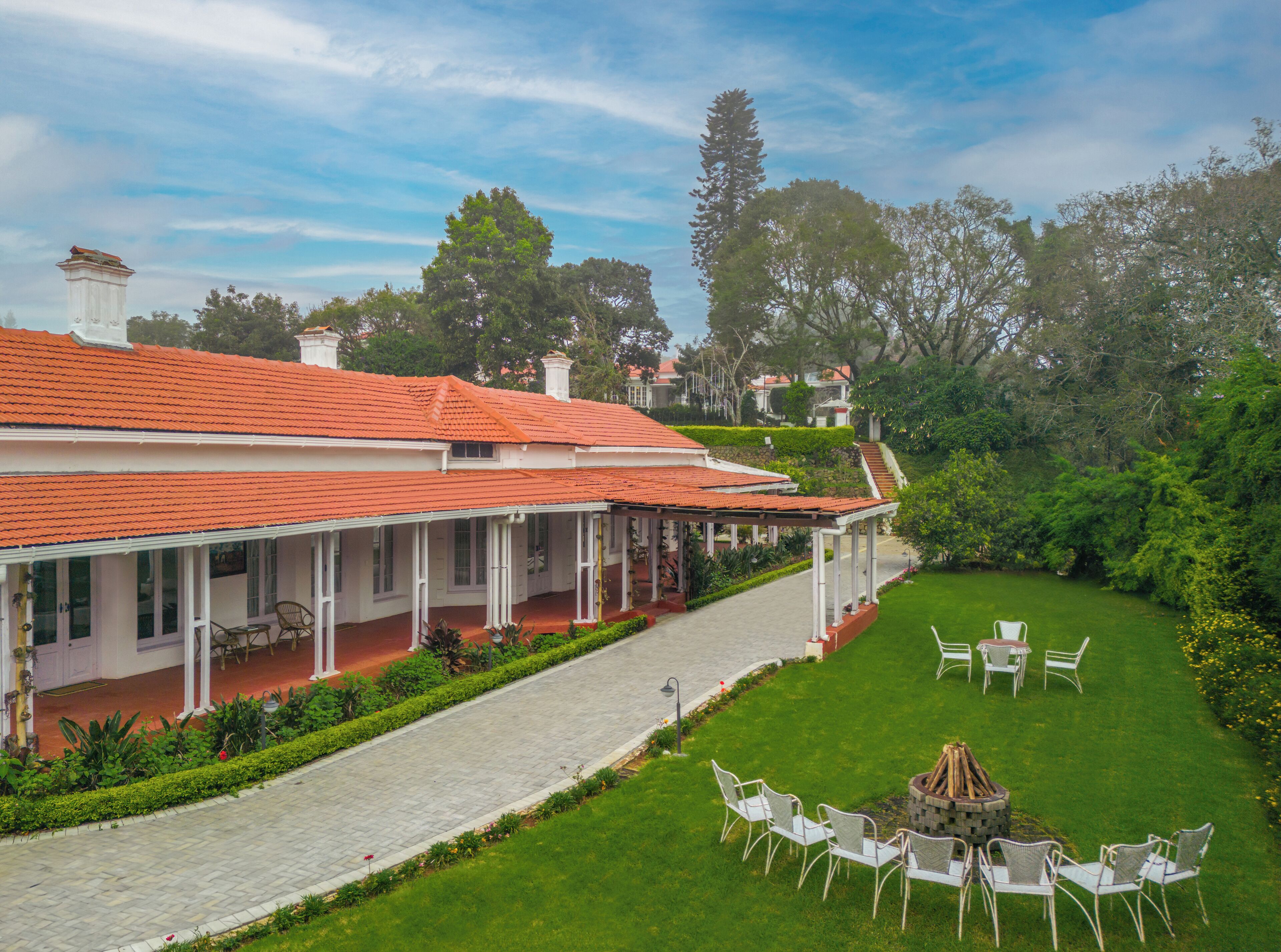 A building with a red-tiled roof, a covered porch, and a well-maintained lawn with outdoor furniture.