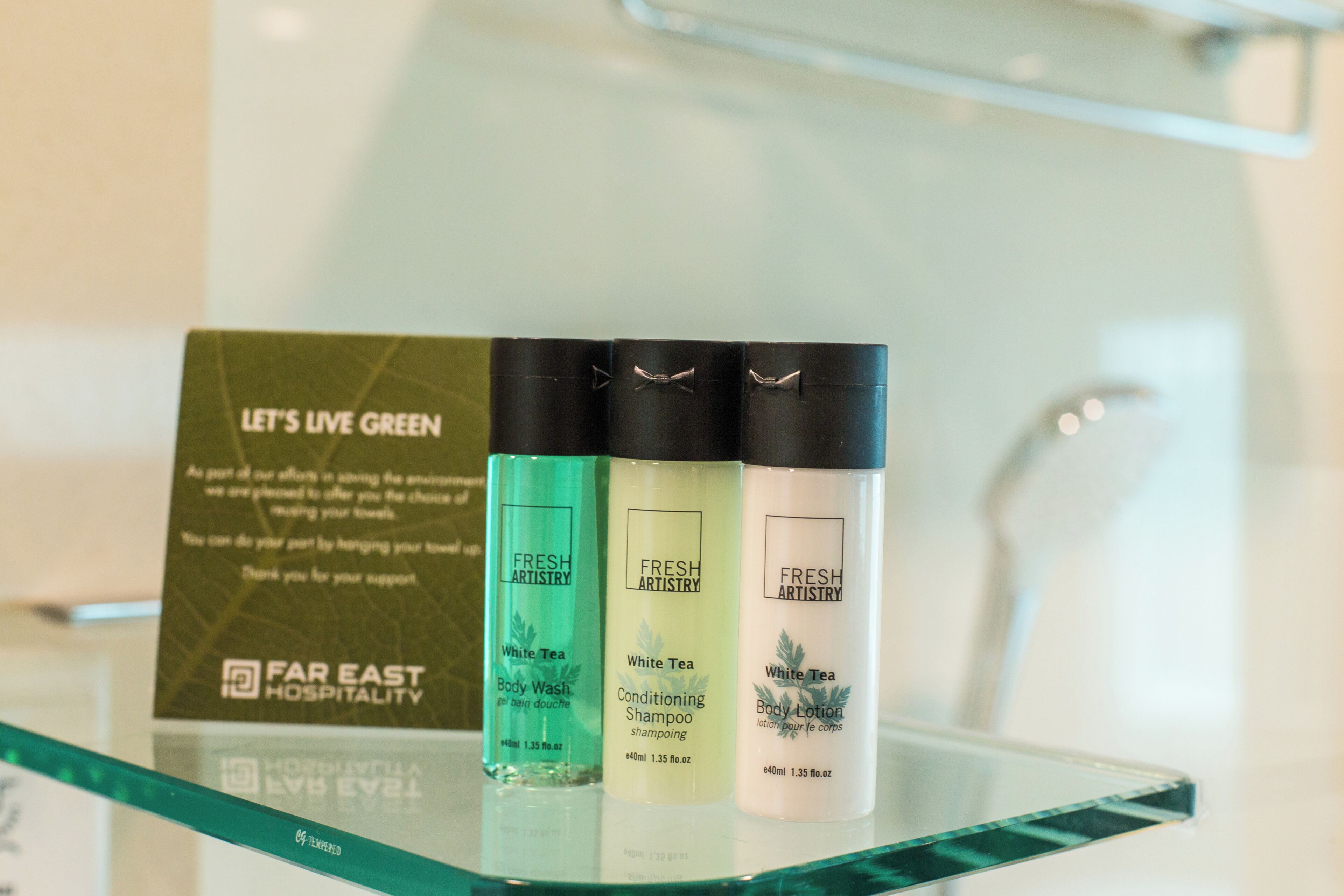 Three bottles of Fresh Artistry body care products on a glass shelf.
