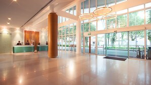 A spacious lobby with a reception desk, large windows, and modern lighting fixtures.