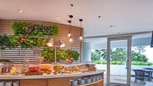 A modern breakfast bar with a wooden finish, surrounded by a lush green vertical garden.