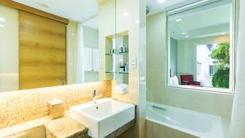 A modern bathroom with a granite countertop, a white sink, a glass shower enclosure, and a large mirror.