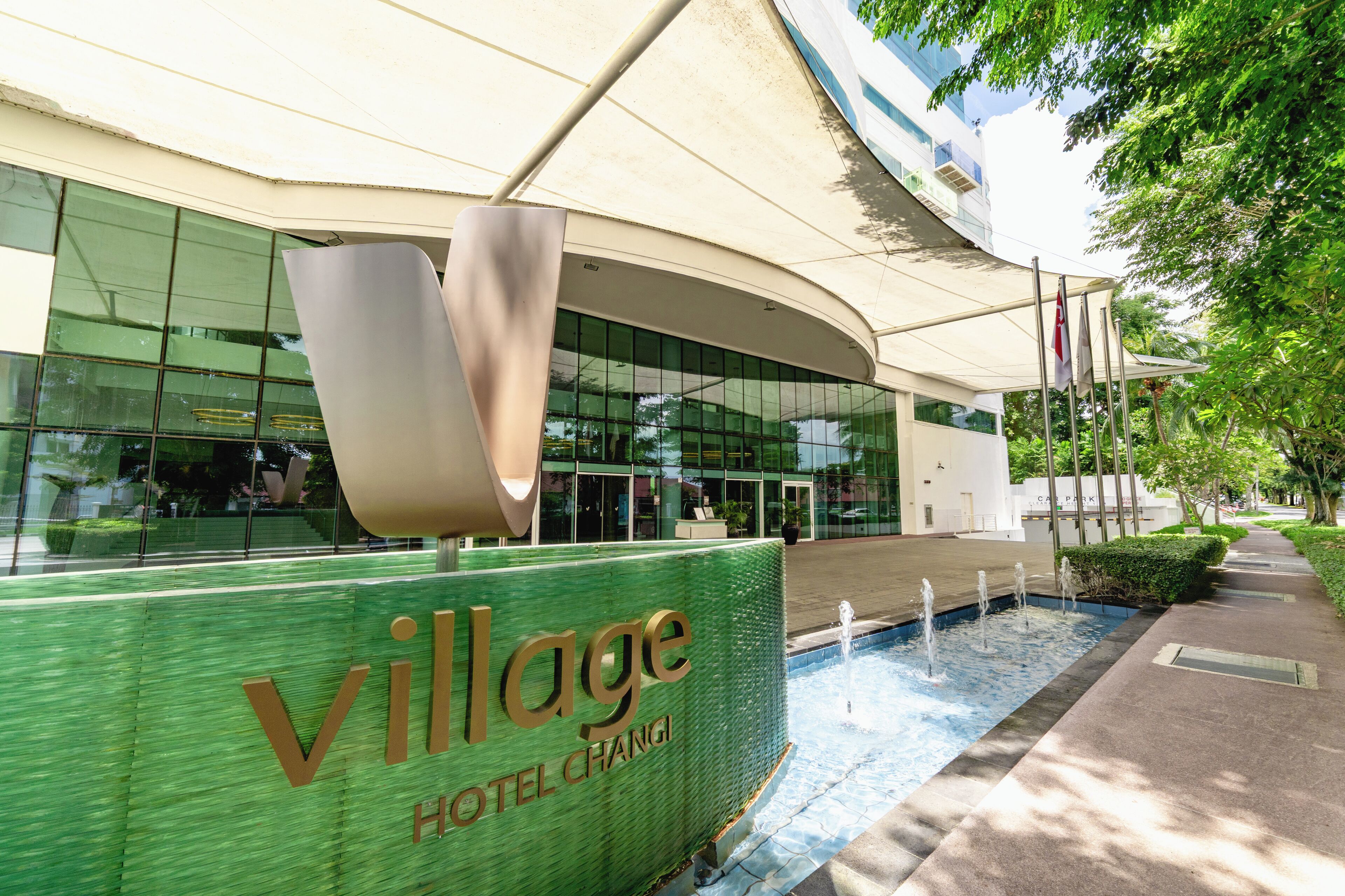 Una entrada moderna de hotel con un cartel grande que dice "Village Hotel Chang".