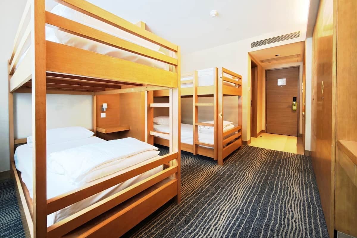 Hotelkamer met stapelbedden, een vloerbedekking en een deur met slot.