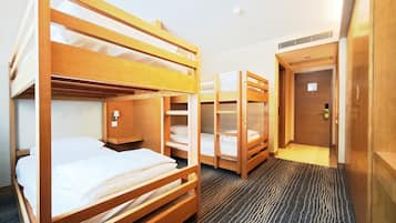 A hotel room with bunk beds, a carpeted floor, a door, and a wall-mounted light fixture.