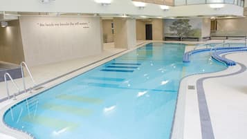 An indoor swimming pool with clear water, a quote on the wall, and a mural of a tree.
