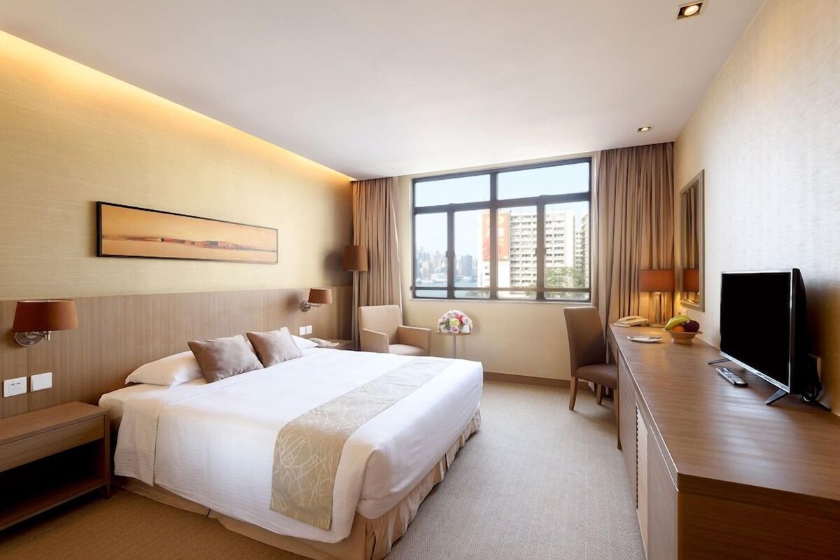 Hotelkamer met een groot bed, een bureau, een televisie en een raam met uitzicht op de stad.