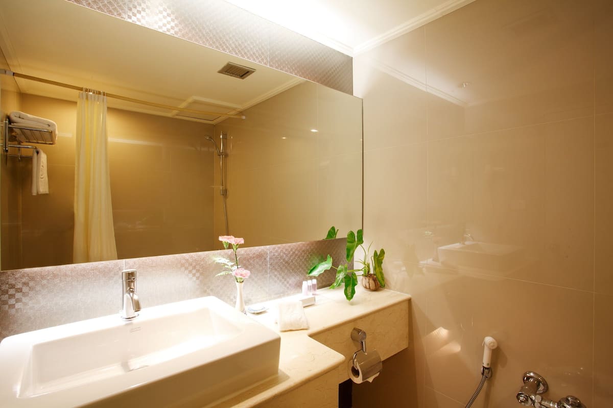 A bathroom with a sink, mirror, shower, and towel rack.