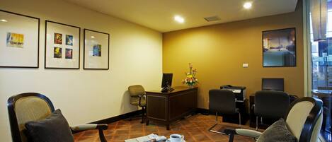 A hotel lobby with a reception desk, seating area, and artwork on the walls.
