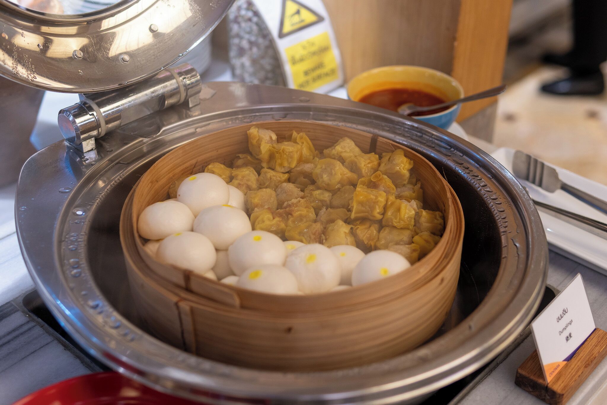 A steamer with dumplings and meat, a warning sign, and a small card.