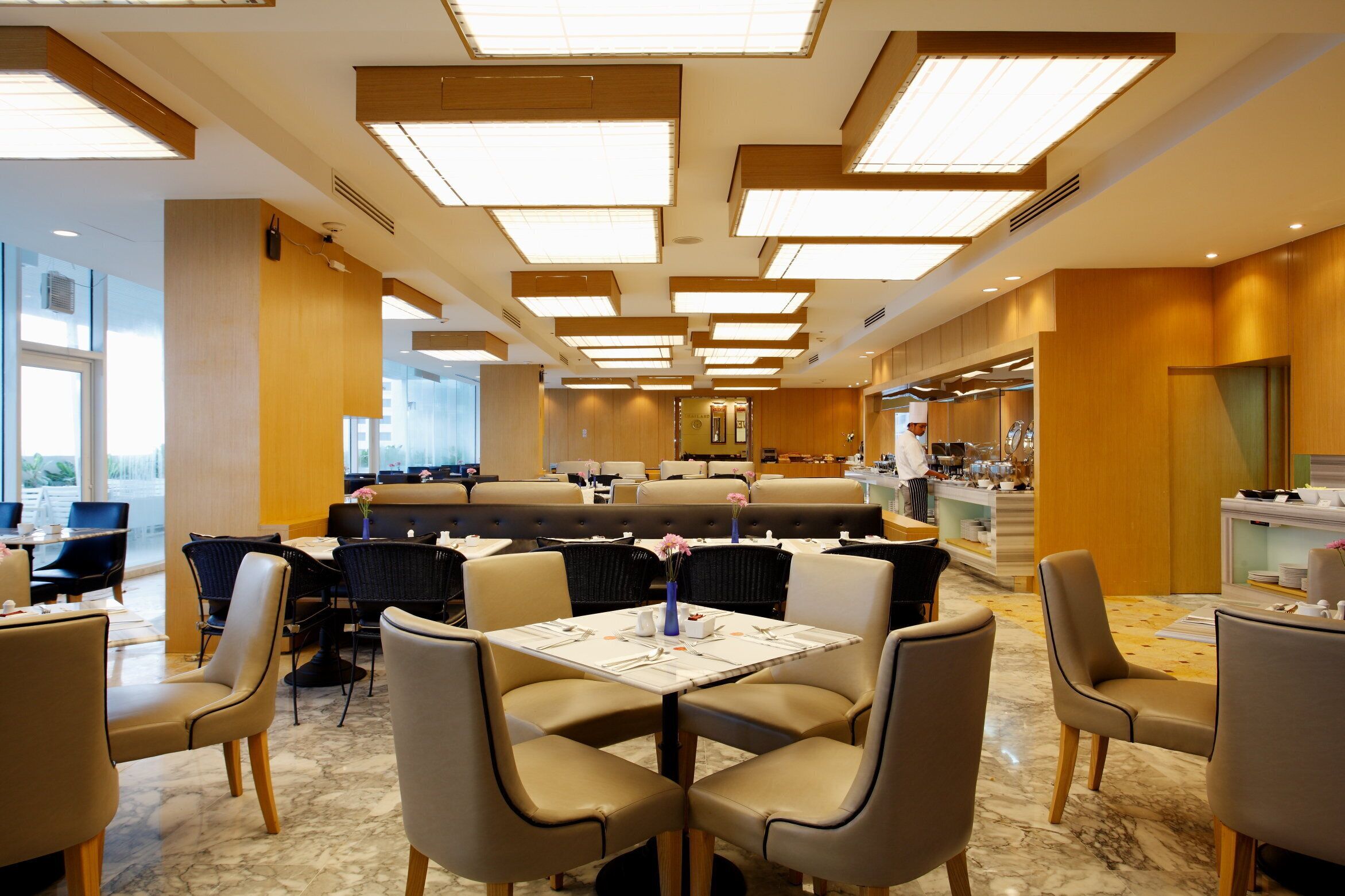 A modern dining area with high ceilings, recessed lighting, and a mix of seating options including tables and booths.
