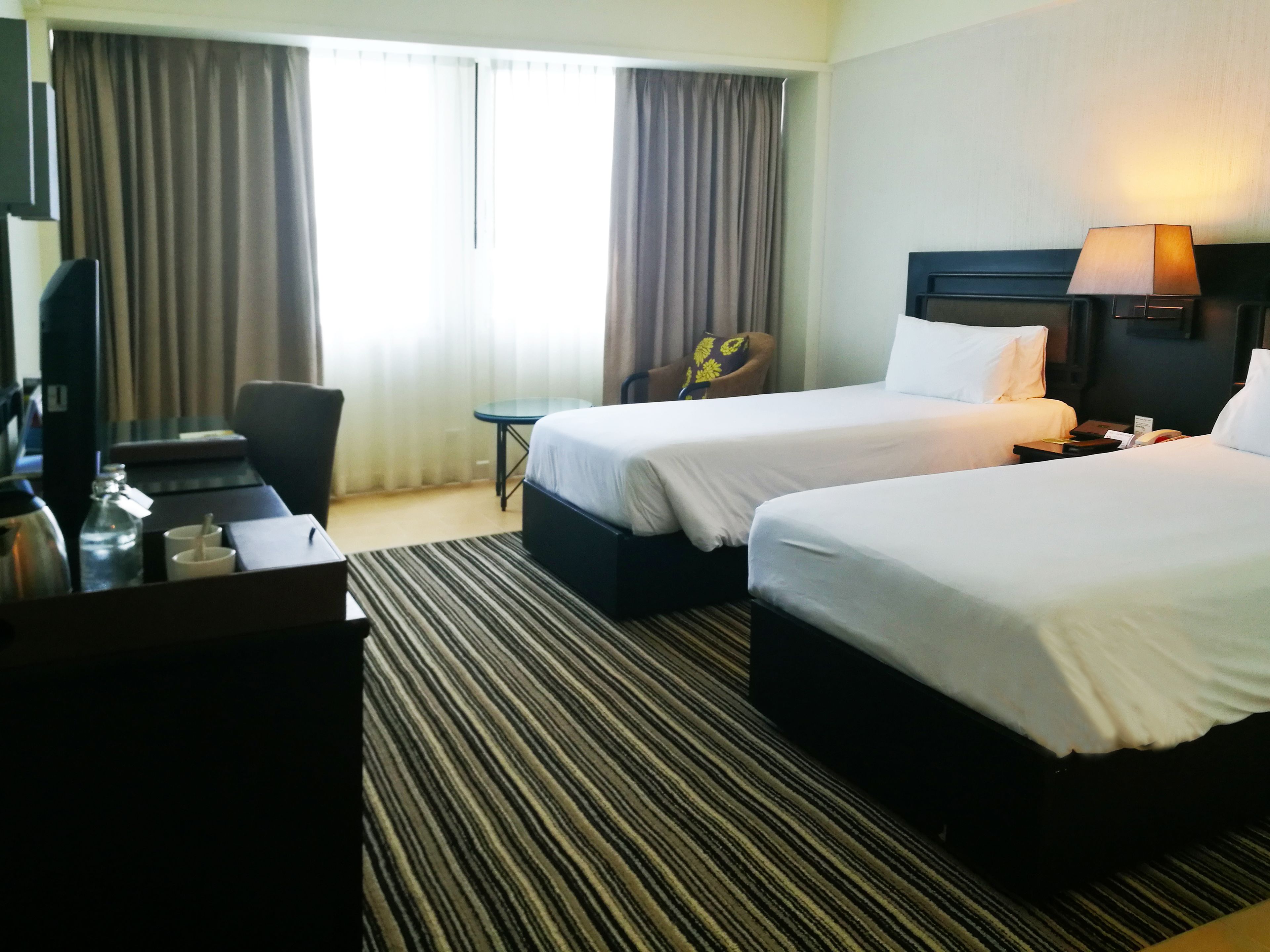 Une chambre d’hôtel avec deux lits, un bureau, une chaise, une télévision et une lampe.