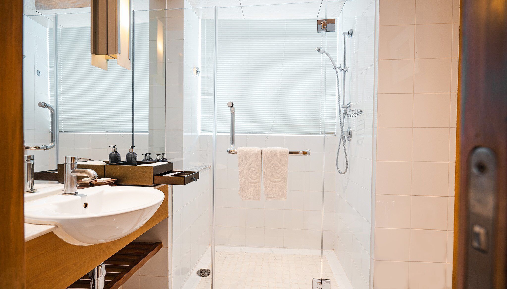 A modern bathroom with a glass shower enclosure, a white sink, and a mirror above the sink.