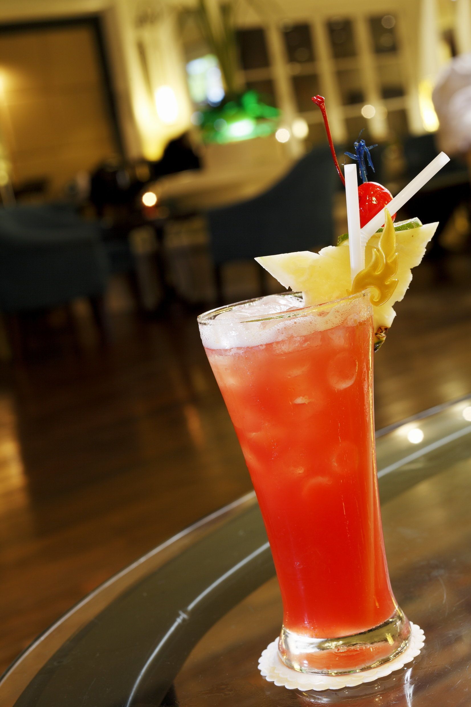 A cocktail with a pineapple garnish and a straw on a glass.
