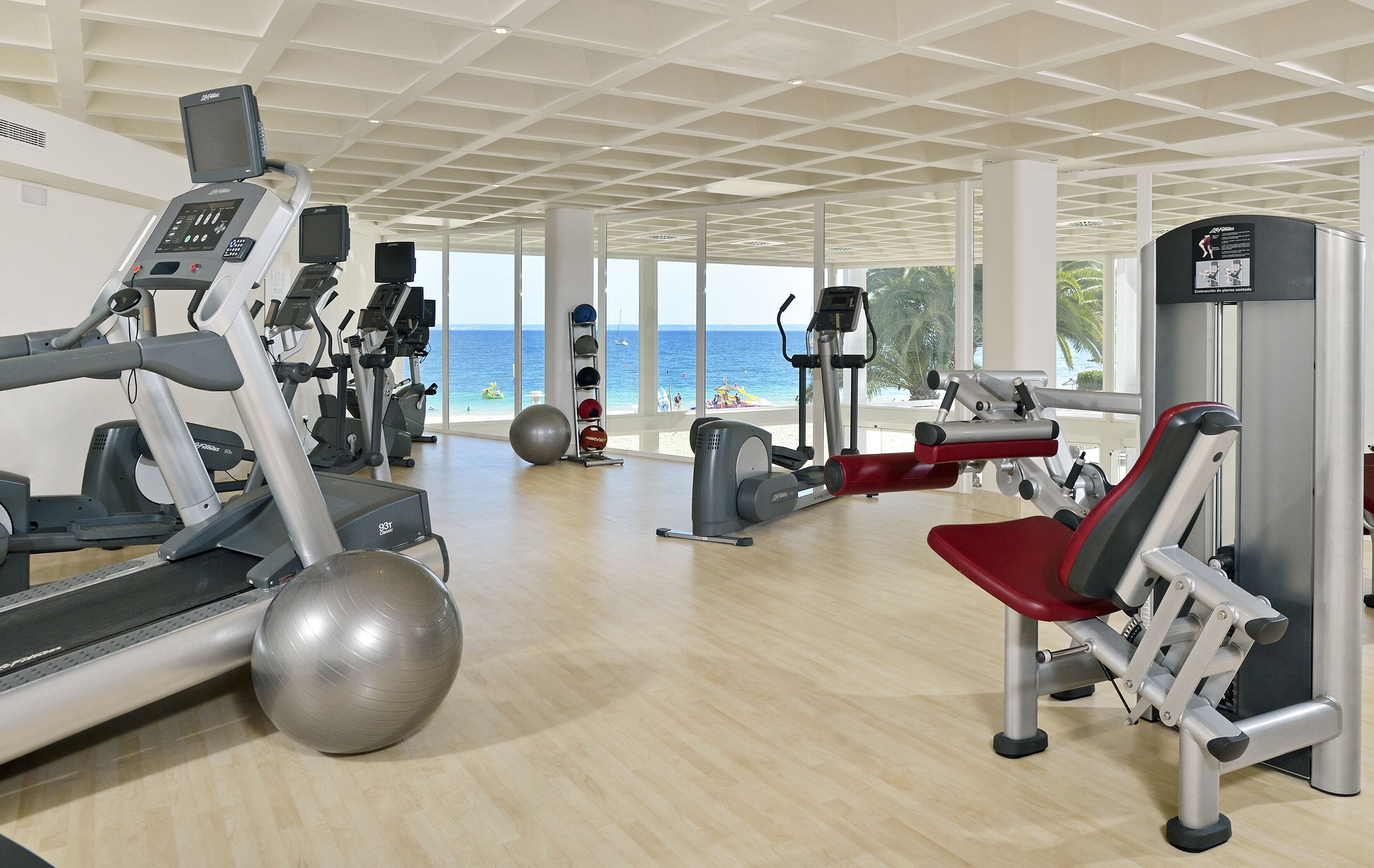 A gym with cardio machines, weight stations, and a large exercise ball.