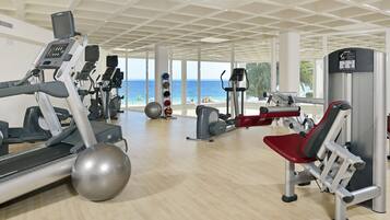 A gym with cardio machines, weight stations, and a large exercise ball.