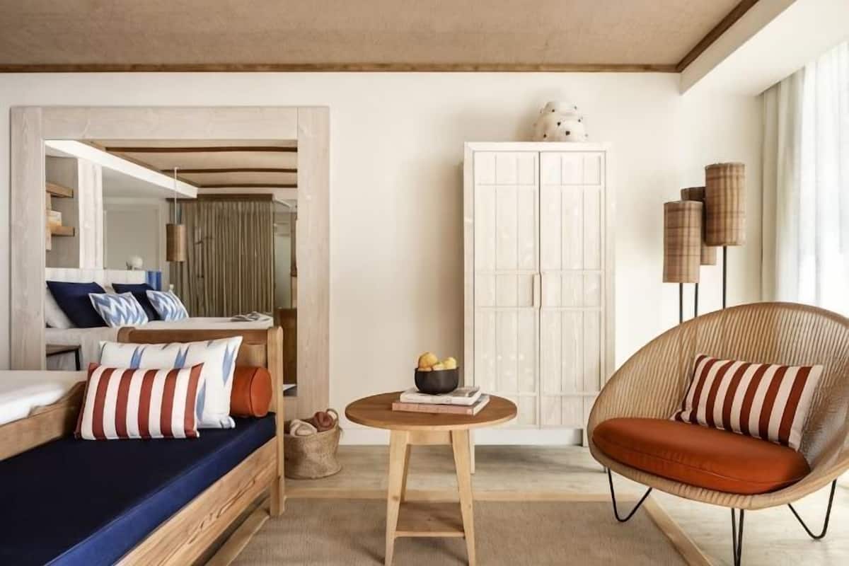 A room with a bed, a chair, a table, and a wardrobe.