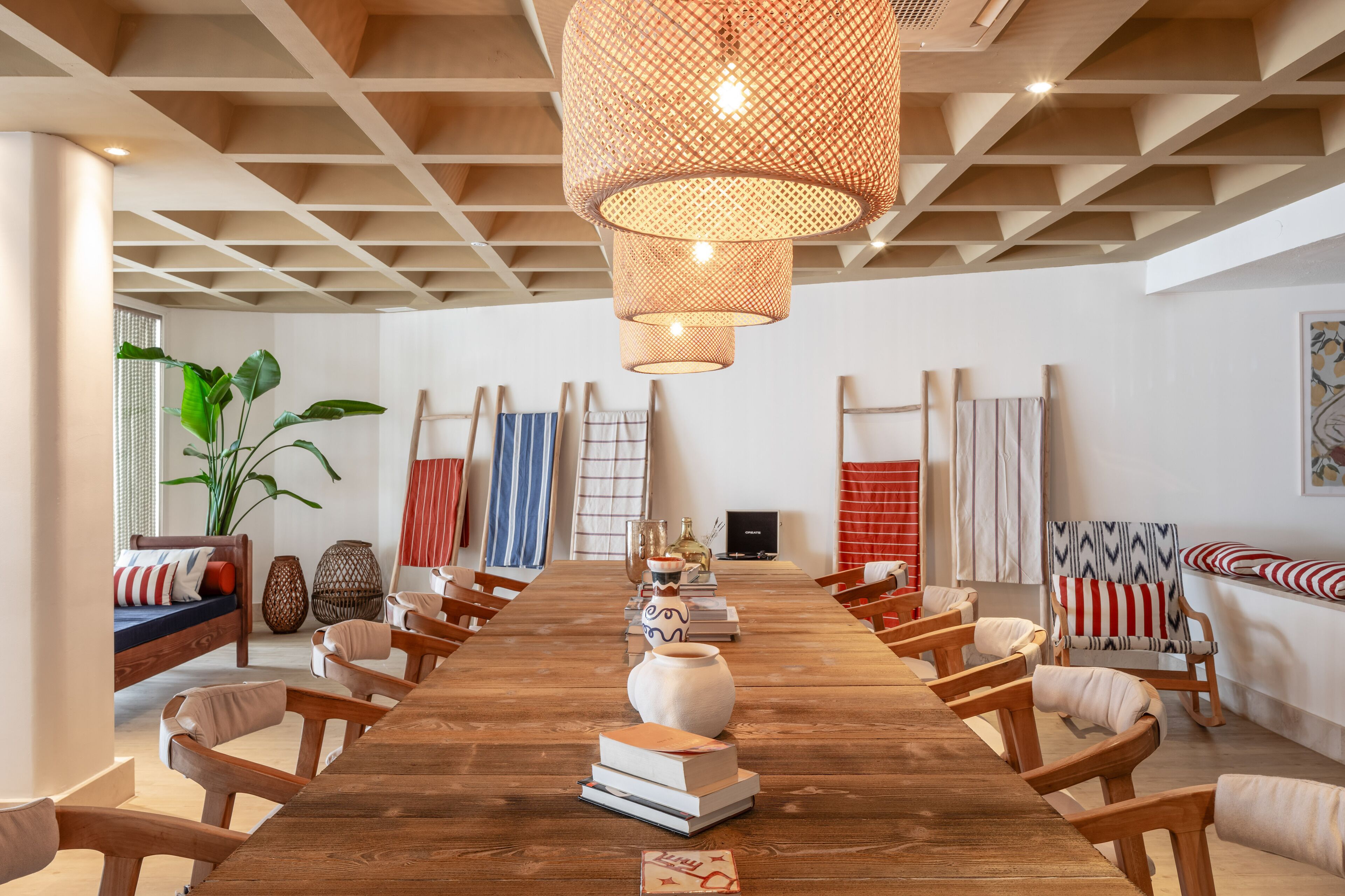 A spacious room with a long wooden table, multiple chairs, and a large woven light fixture.
