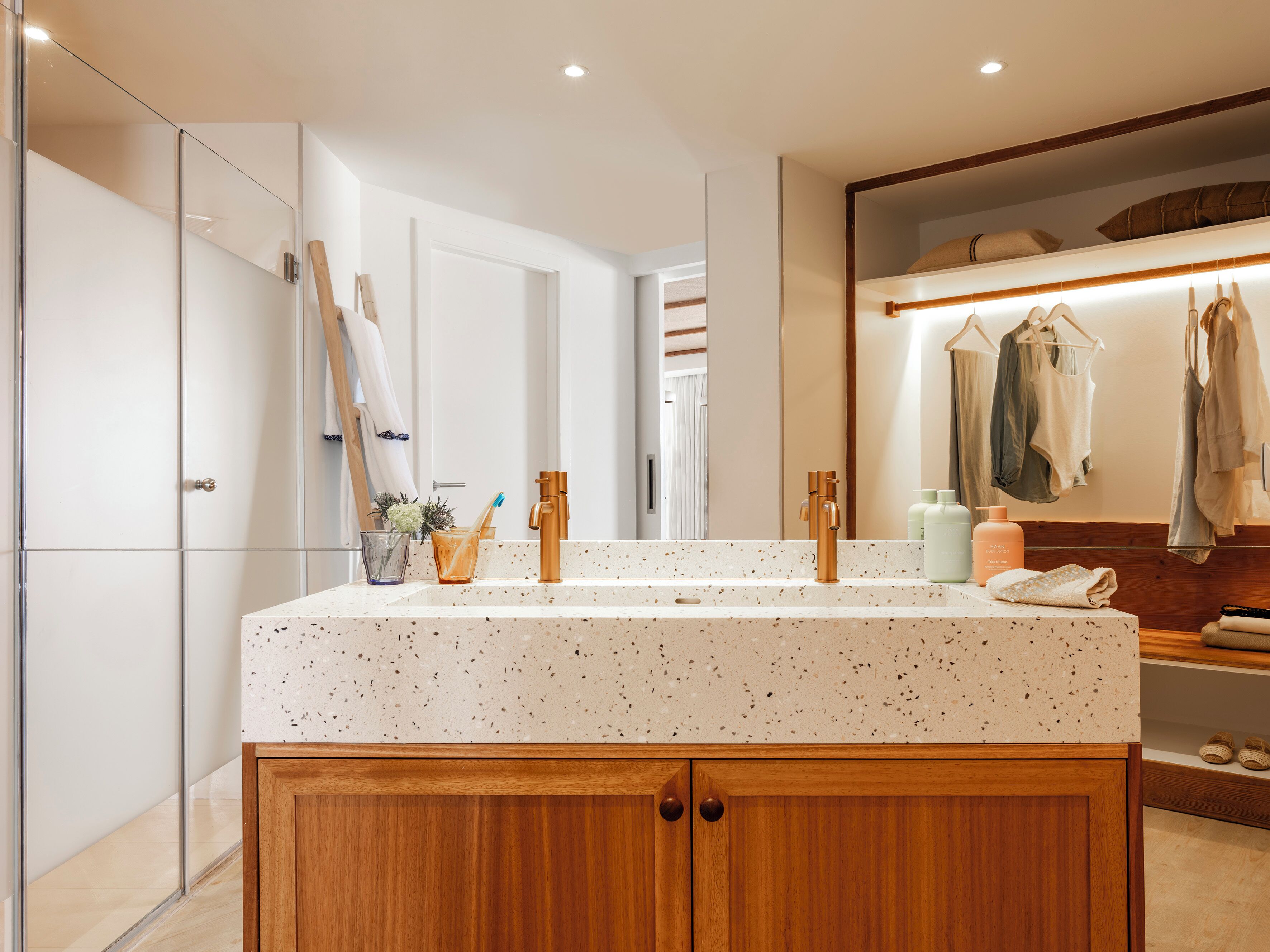 Un baño moderno con un espejo grande, armarios de madera y una encimera con artículos de aseo.