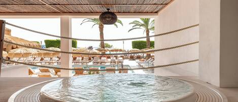Ett poolområde med solstolar och en bubbelpool.