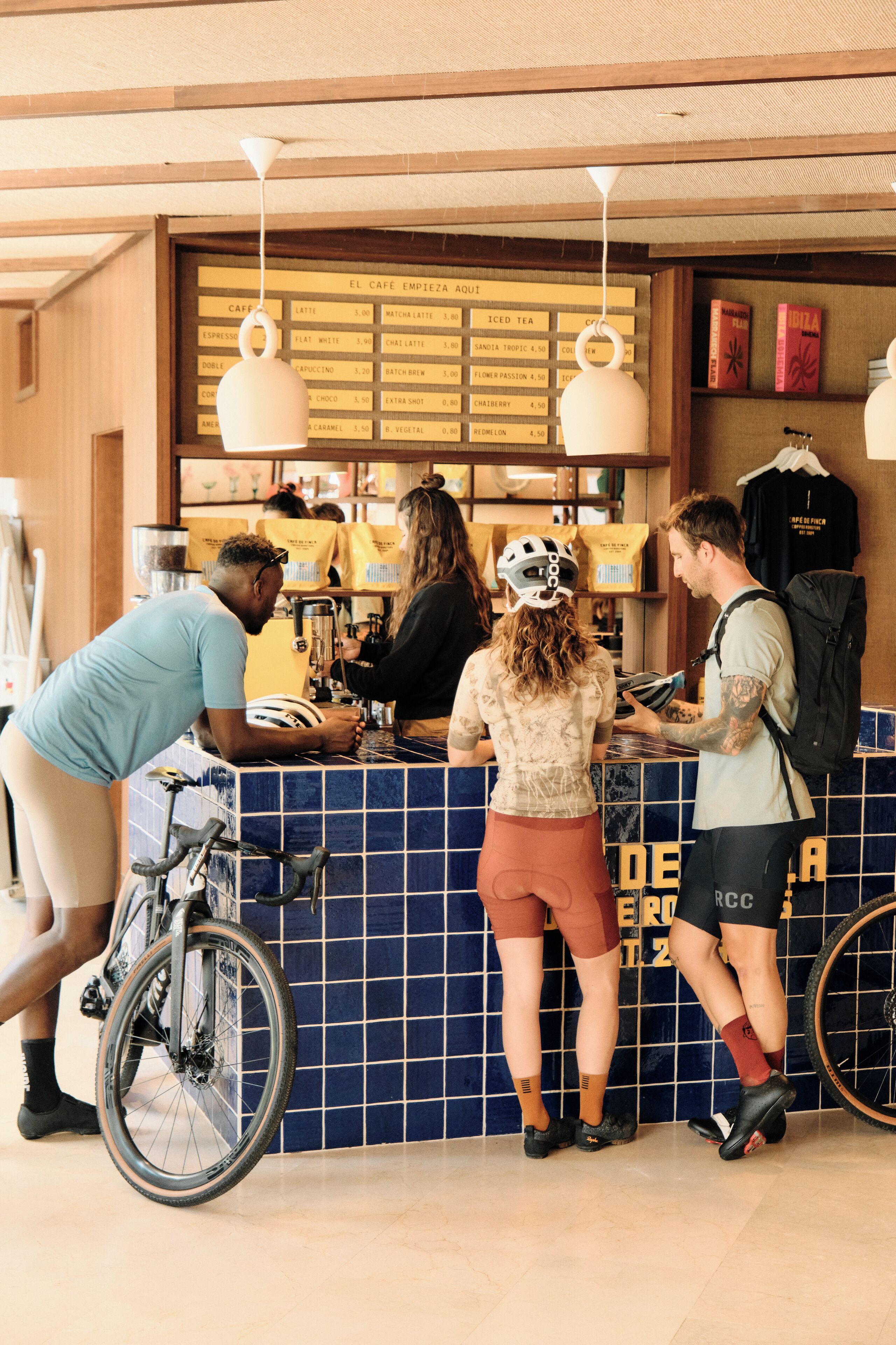 A cafe counter with a menu board, a bicycle, and people interacting.