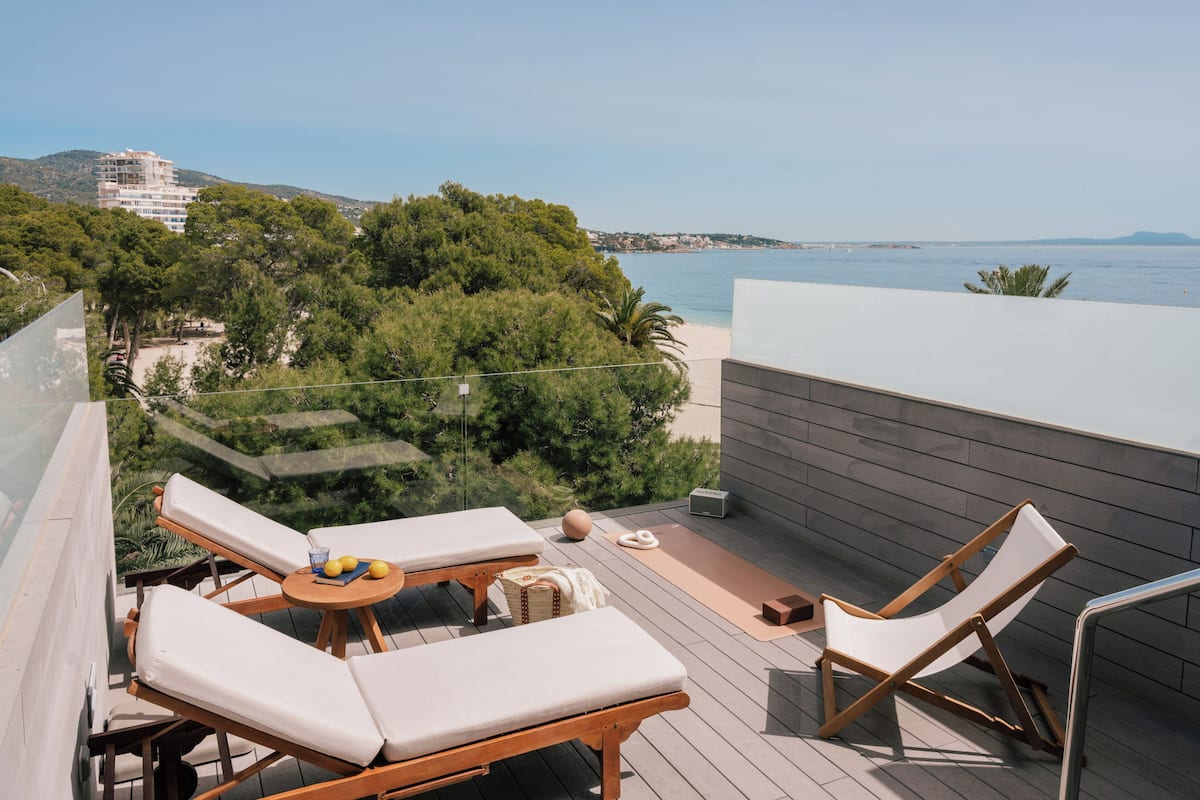 A balcony with lounge chairs, a small table with lemons, and a yoga mat.