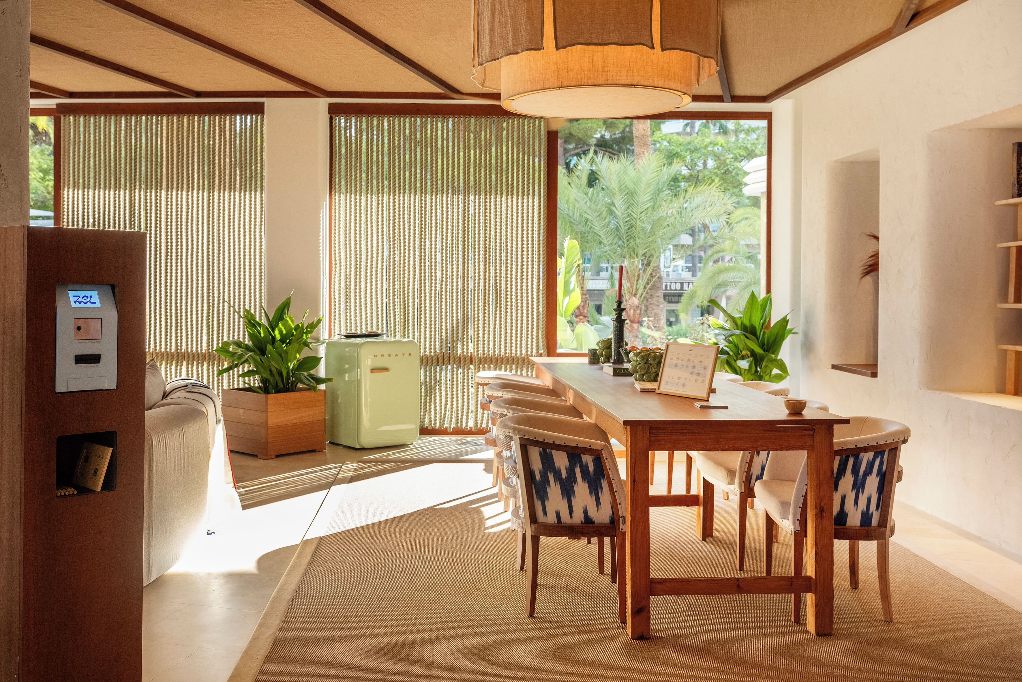 Un comedor moderno con una mesa y sillas de madera, un refrigerador verde y plantas en macetas.