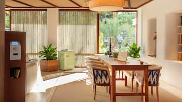 Un comedor moderno con una mesa y sillas de madera, un refrigerador verde y plantas en macetas.