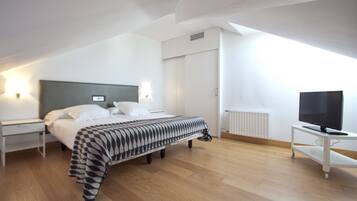 Quarto de hotel moderno com uma cama grande, televisão e escrivaninha.