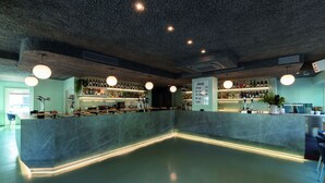 A bar area with a marble counter, shelves of bottles, and hanging lights. - Hotel Jauregui (Hondarribia)