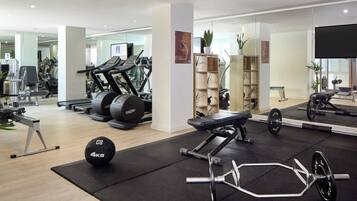 A modern gym with cardio machines, weightlifting equipment, and a mirrored wall.