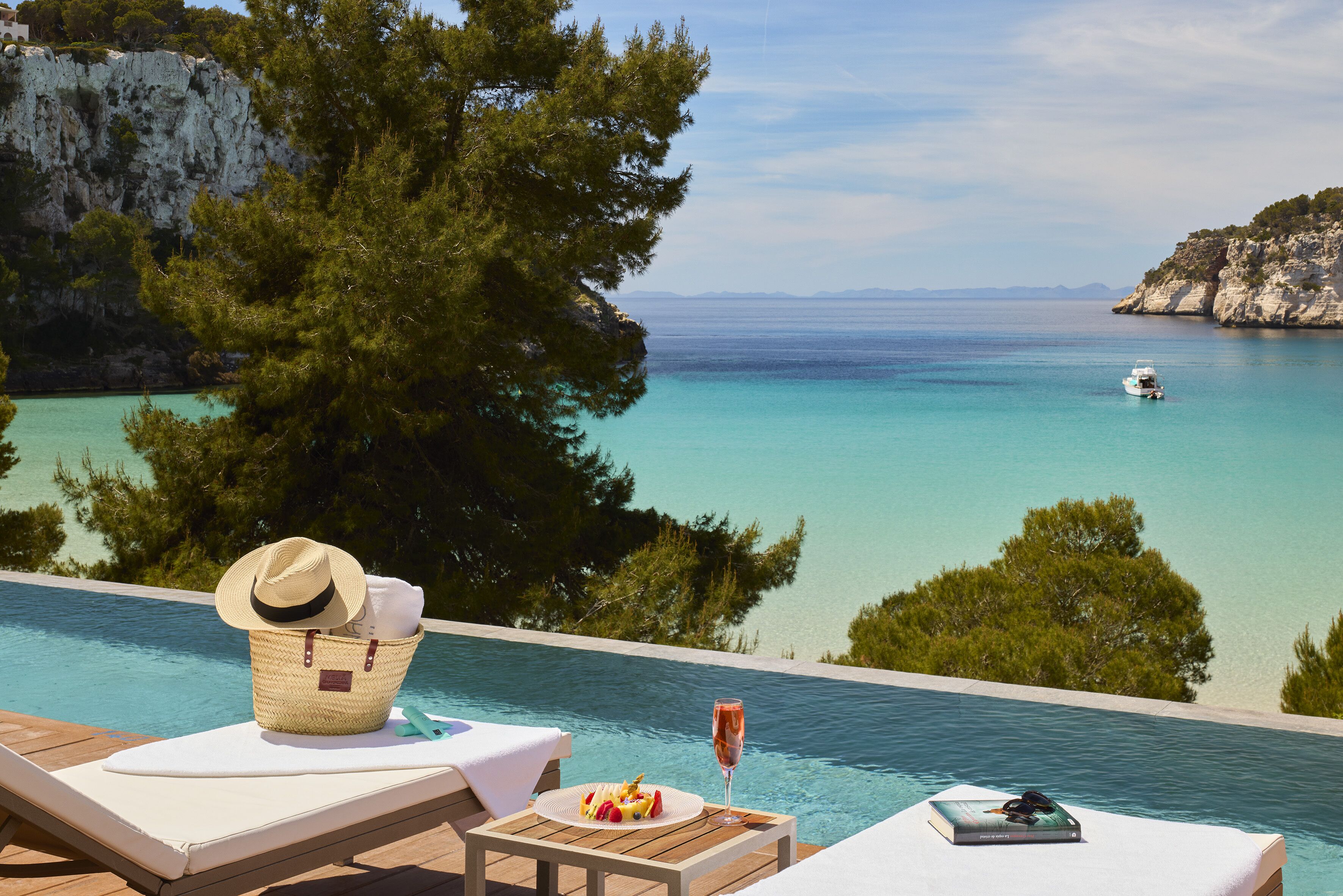 Un espace aménagé au bord de la piscine offrant une vue sur la mer, la plage et une falaise.