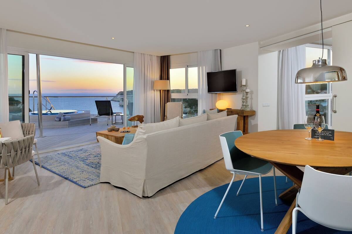 Ein modernes Hotelzimmer mit Balkon, Essbereich und Fernseher.