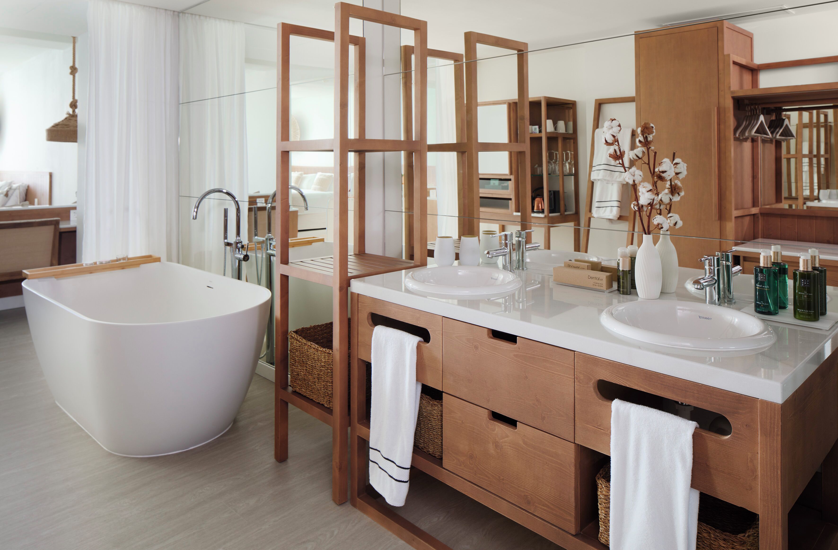 A modern bathroom with a freestanding bathtub, two sinks, and a large mirror.