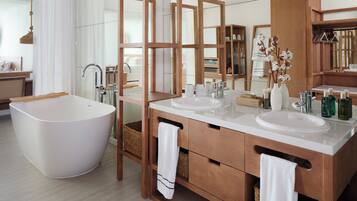 A modern bathroom with a freestanding bathtub, two sinks, and a large mirror.