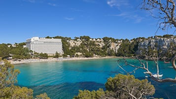A coastal hotel with a view of the sea and a cliff.