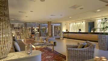 A spacious lobby with wicker furniture, a reception desk, and decorative lighting.