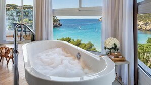 Un baño moderno con una bañera grande, cabina de ducha de cristal y vistas al mar.