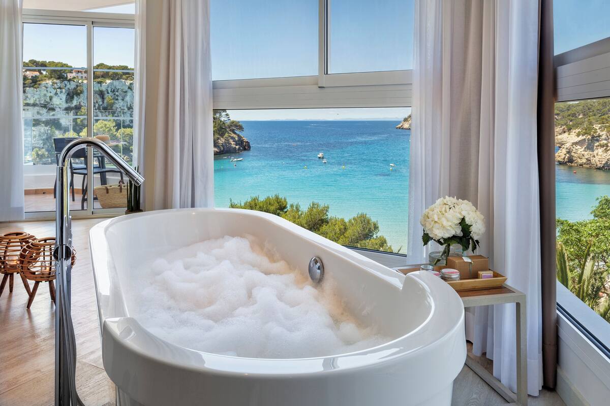 Ein modernes Badezimmer mit einer großen Badewanne, einer Duschkabine aus Glas und Meerblick.