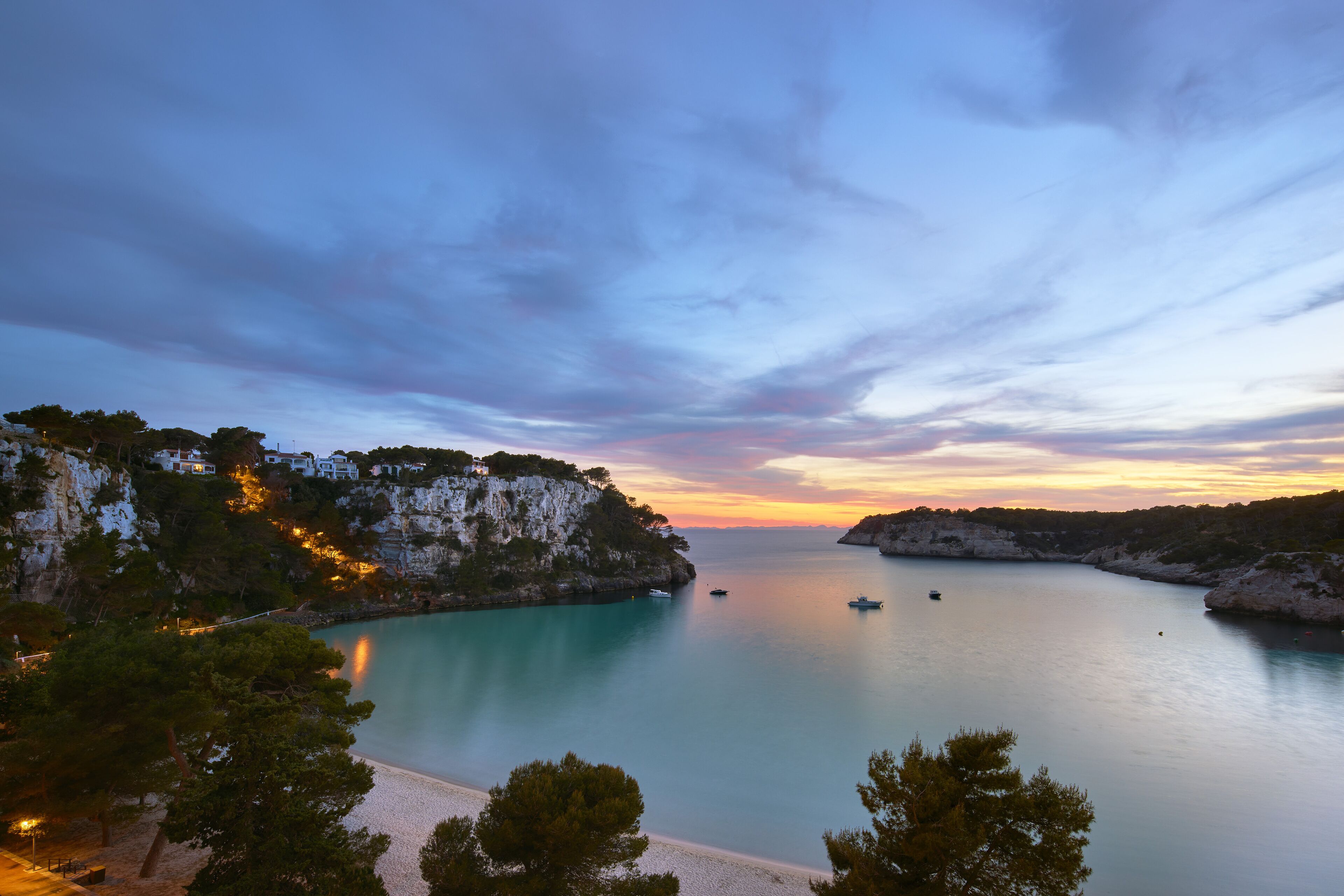 A coastal landscape with a clear sky, calm sea, and rocky cliffs.