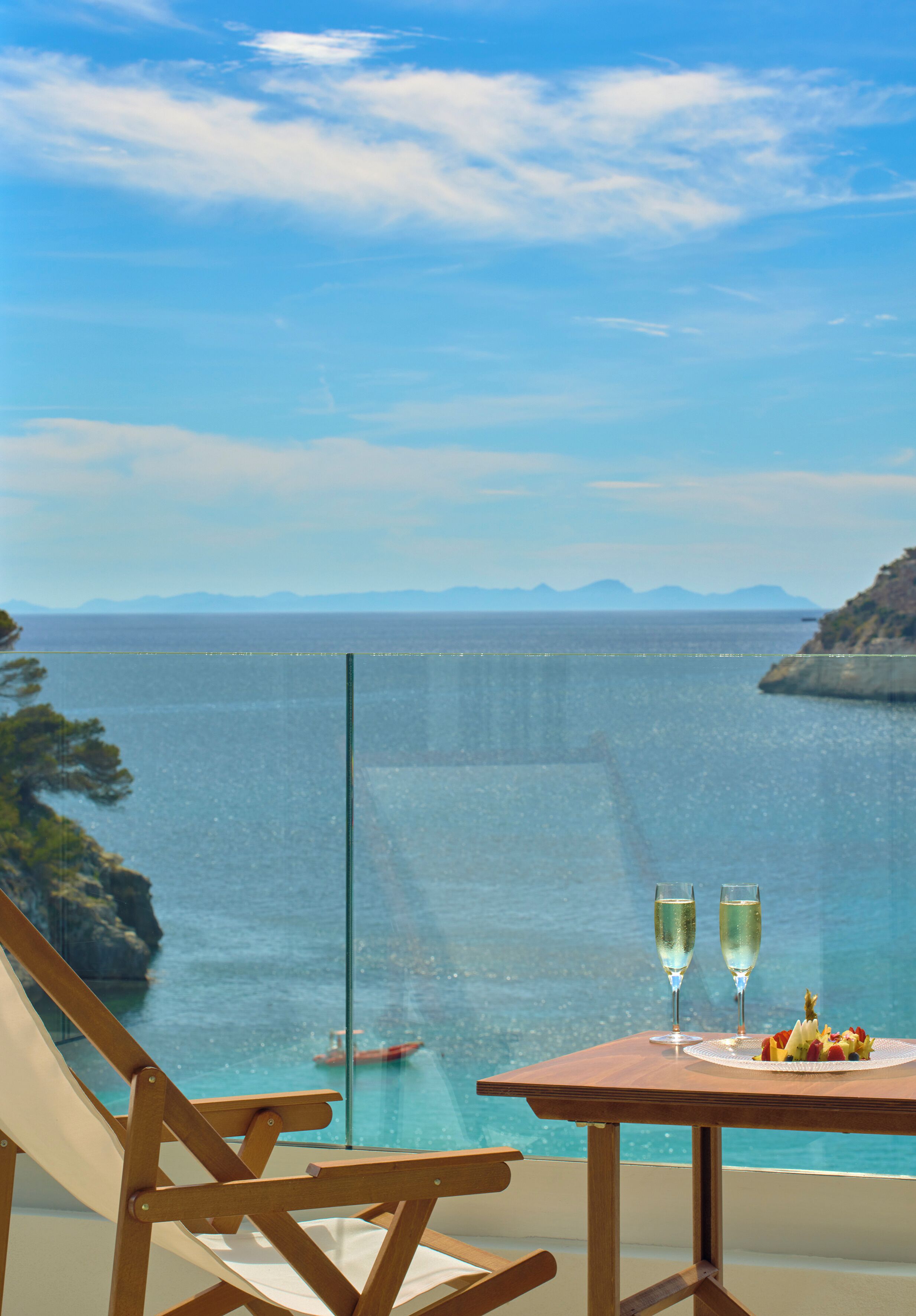 A balcony with a table, two glasses of champagne, and a plate of fruit.