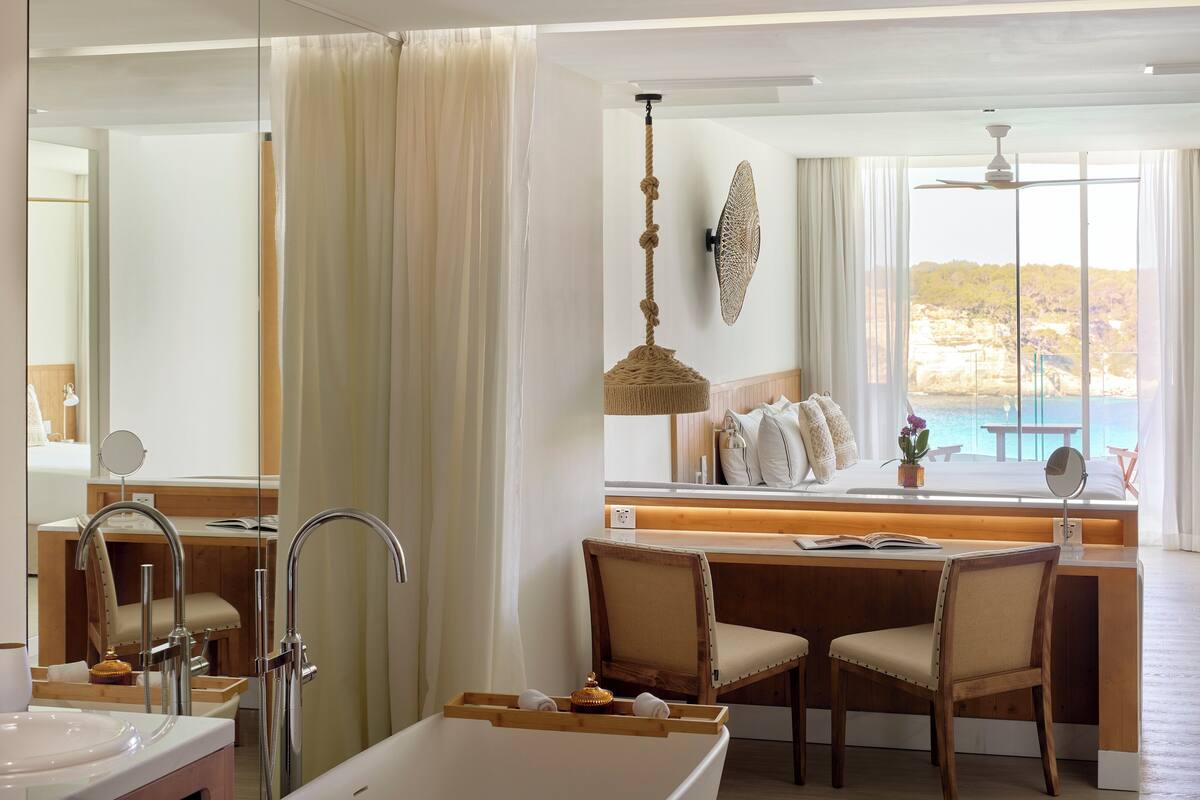 Ein modernes Badezimmer mit Badewanne, Waschtisch und einer Sitzecke mit Meerblick.